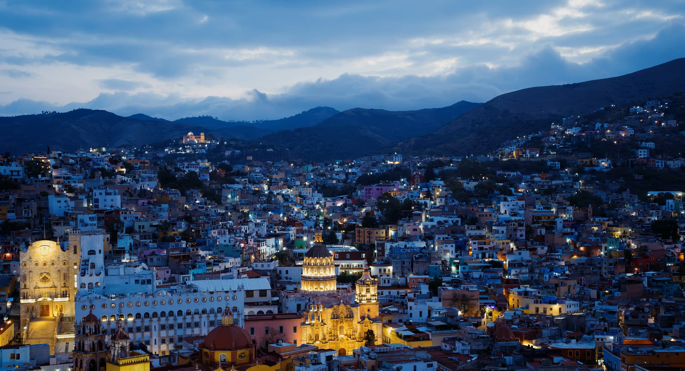 Guanajuato al anochecer: casas de colores en los cerros con las luces encendiéndose
